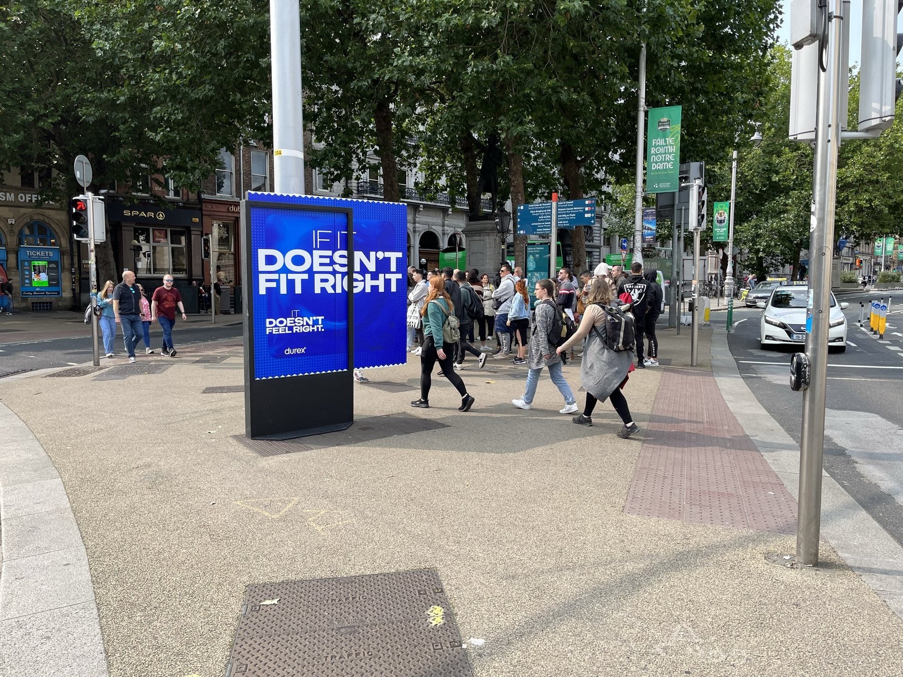 People walking past a Durex panel at College Green, Dublin.