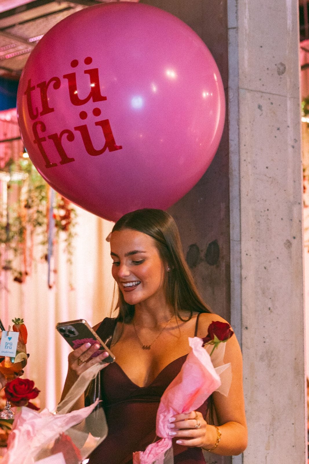 A guest under a pink Trü Frü balloon, holding a rose.