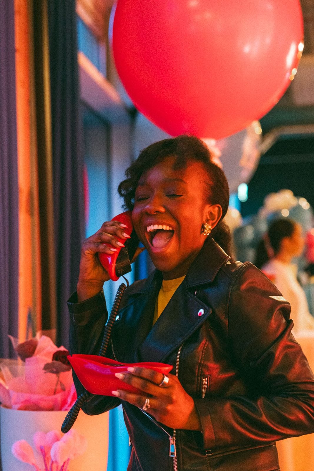 A guest laughing at the Galentines event, a red balloon behind her.