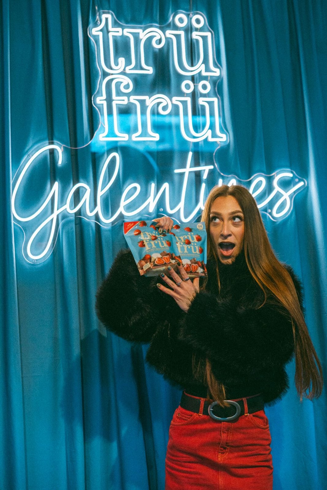 A guest holding a pack of Trü Frü under the neon Galentines sign.