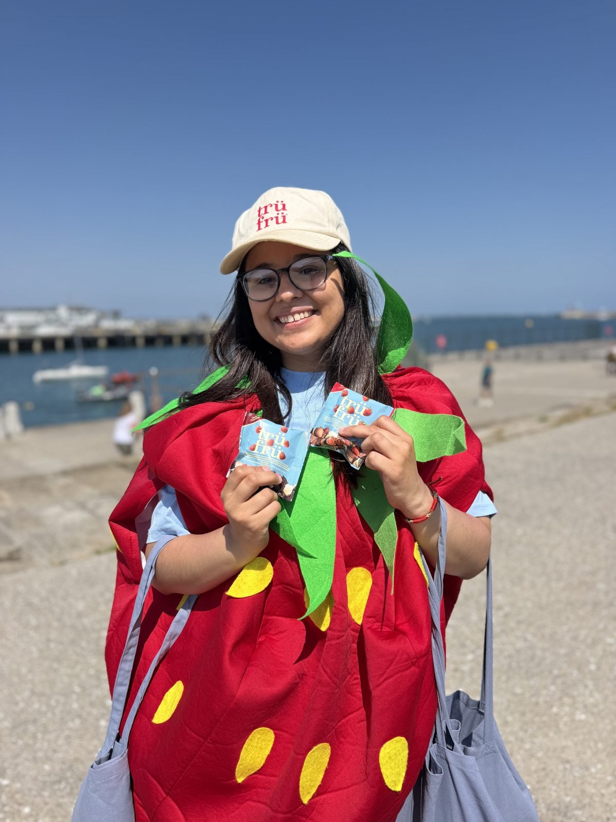 A team member in a strawberry costume handing out packs on the seafront.