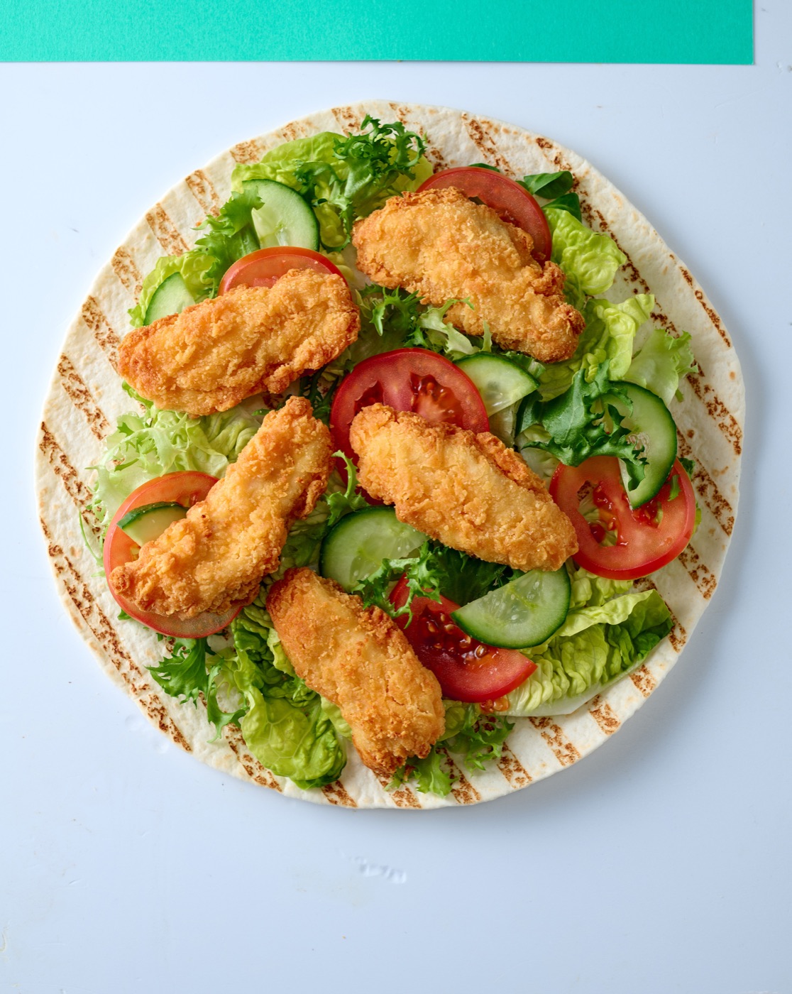 Chicken with Attitude golden tenders served on a flatbread with salad.