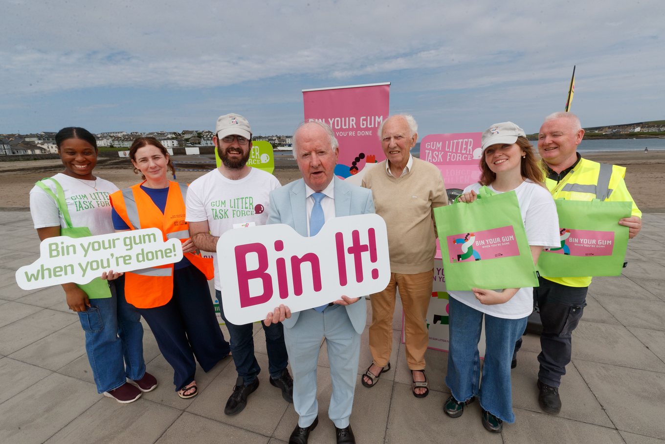 Brand ambassadors, council staff and local representatives on the promenade holding Bin It! placards.