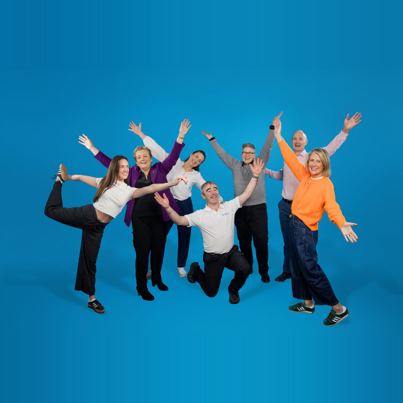 Members of the Irish Society of Chartered Physiotherapists, arms raised, on a blue studio ground.