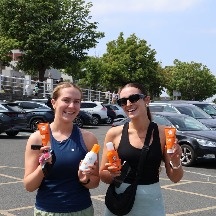Two women holding bottles of Cien they have just been given, the van behind them in Galway.