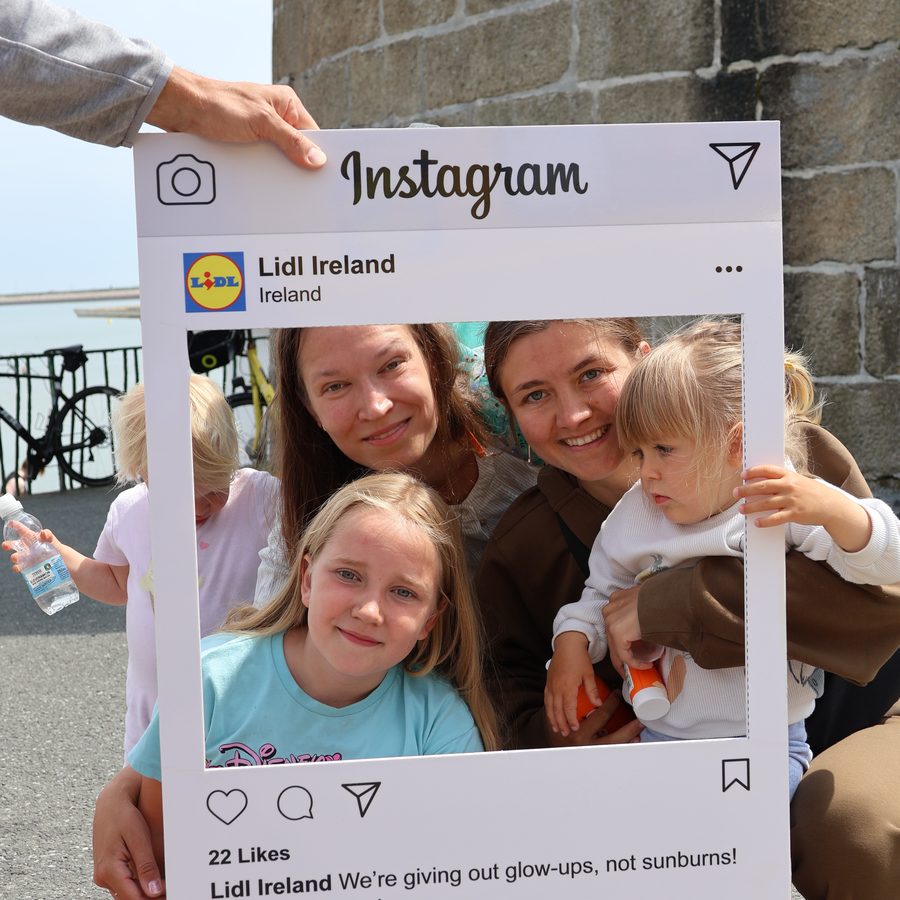 A family posing in a giant Instagram frame reading, we are giving out glow-ups, not sunburns.