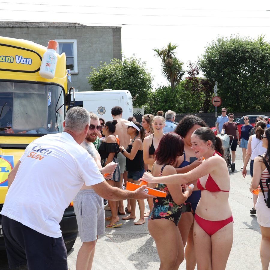 Swimmers in swimwear queueing at the Sun Cream Van on a hot day.